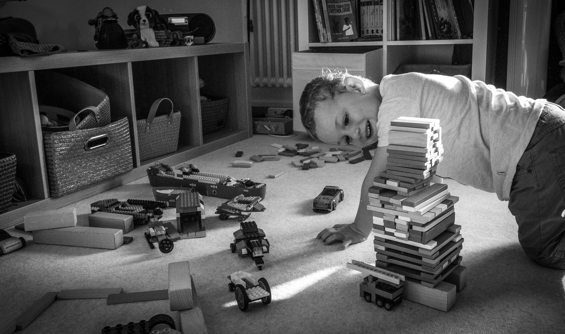 Enfant jouant dans sa chambre avec des éléments en bois.