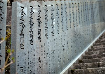 Un escalier bordé de stèles de granit frappées d'idéogrammes kanji.