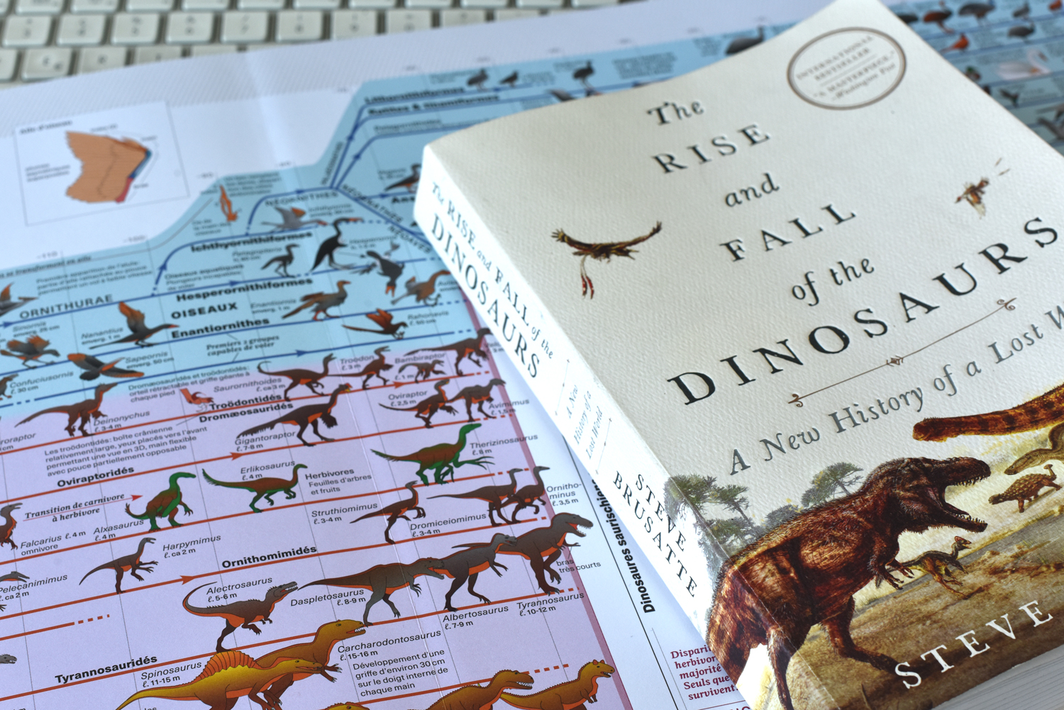 le livre «Le triomphe et la chute des dinosaures» de Steve Bursatte posé sur une planche de l'Atlas des vertébrés