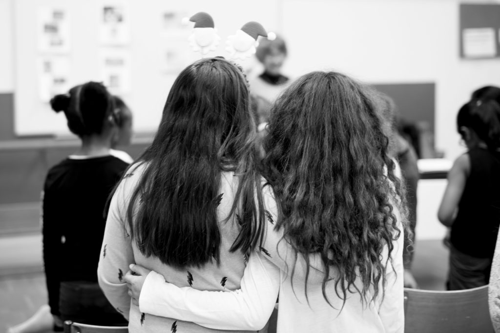 Deux filles se tiennent par la taille durant un cours de chant.